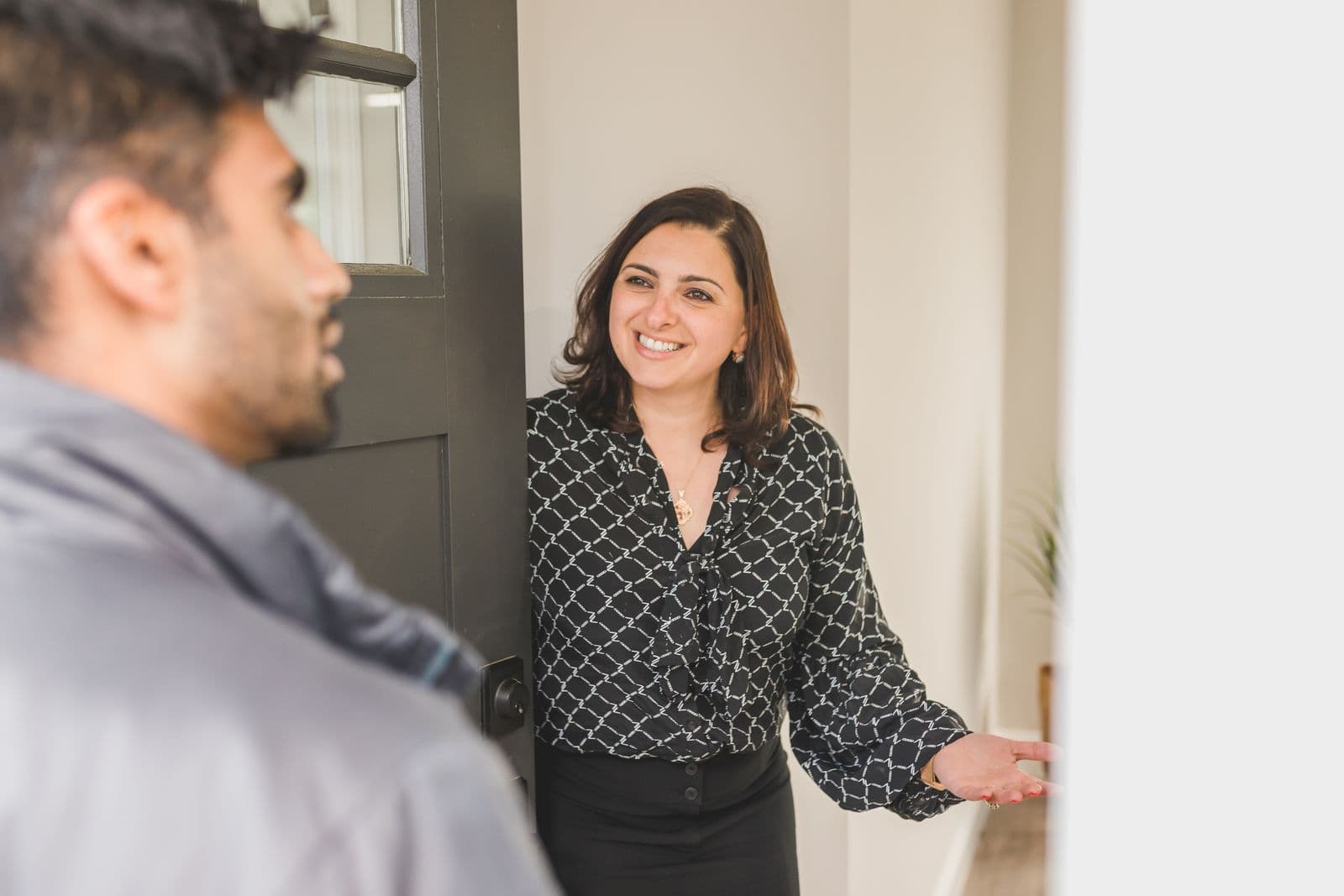 A real estate agent welcomes a client into a home for a viewing.
