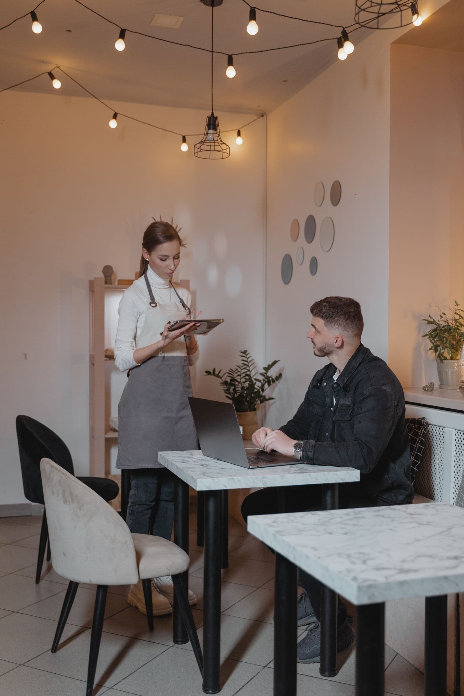 A restaurant server takes an order from a guest at a café table.