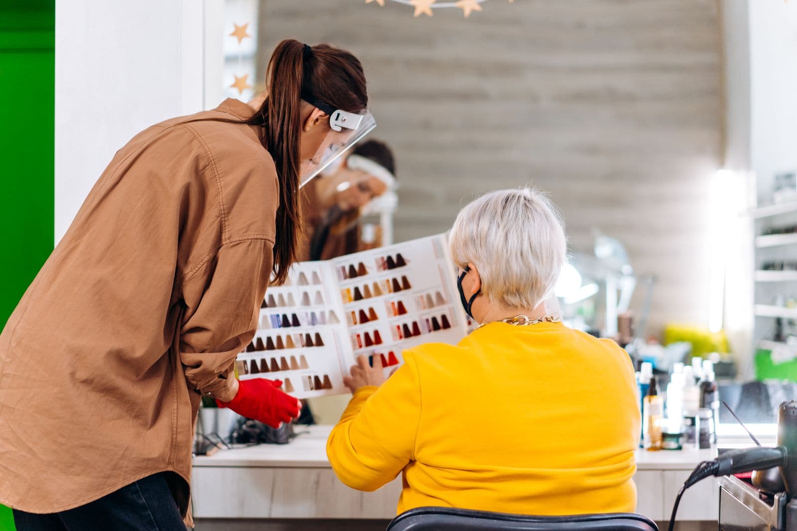 A stylist discusses hair color options with a salon client.